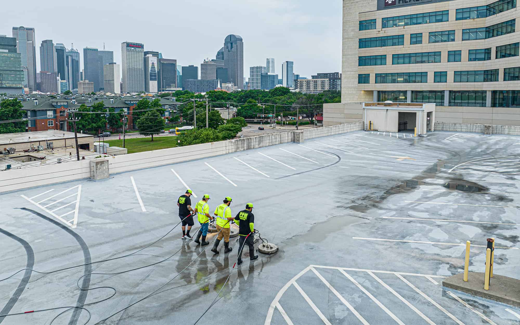 Aerial view of four men cleaning a top level parking lot