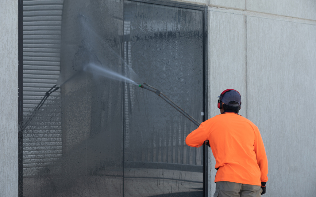 Back view of a man power washing windows