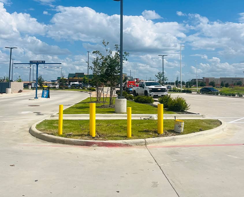 Front view of four yellow bollards in parking lot