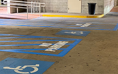 Accessible parking with blue symbols, ramp, and trash bin