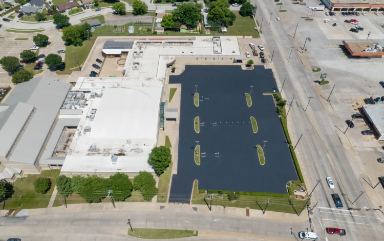 Aerial view of a freshly paved parking lot by a white building