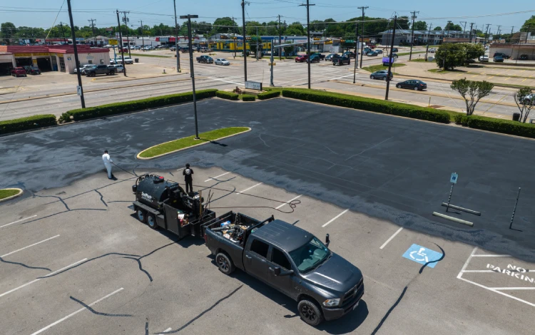 Aerial view of a freshly sealed parking lot with a pickup and equipment
