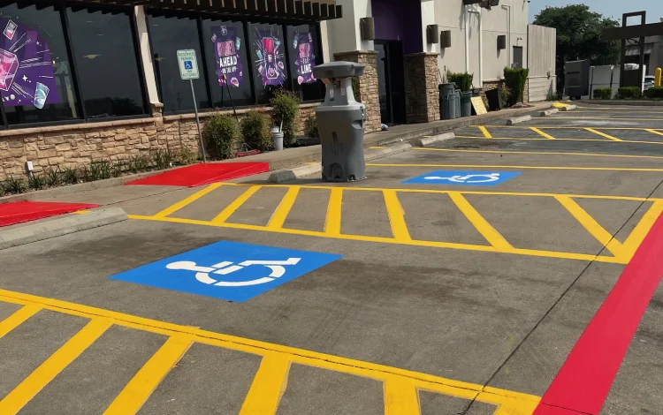 Parking lot with two handicap signs, yellow lines, and red curbs