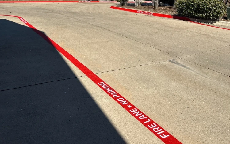 Paved area with red curb under bright sunlight.