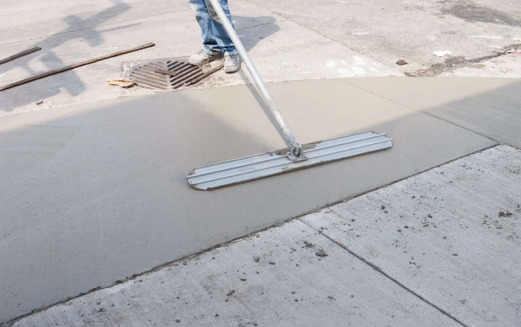 PPM technician smoothing wet concrete on a sidewalk during concrete repair