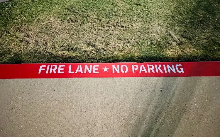 Red curb with white text Fire Lane - No Parking in bold letters.