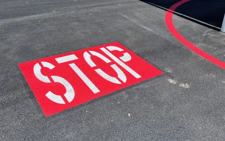 White STOP painted on a red rectangle on asphalt