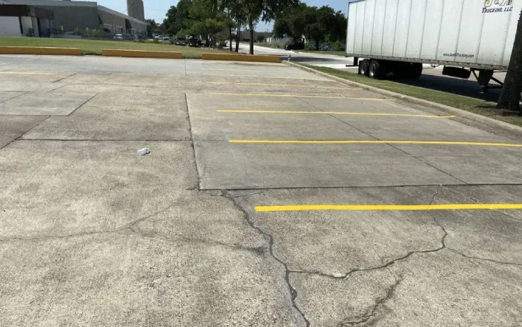 Cracked concrete parking lot with faded yellow lines