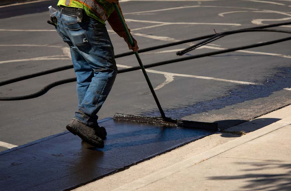 workers applying sealcoating on asphalt